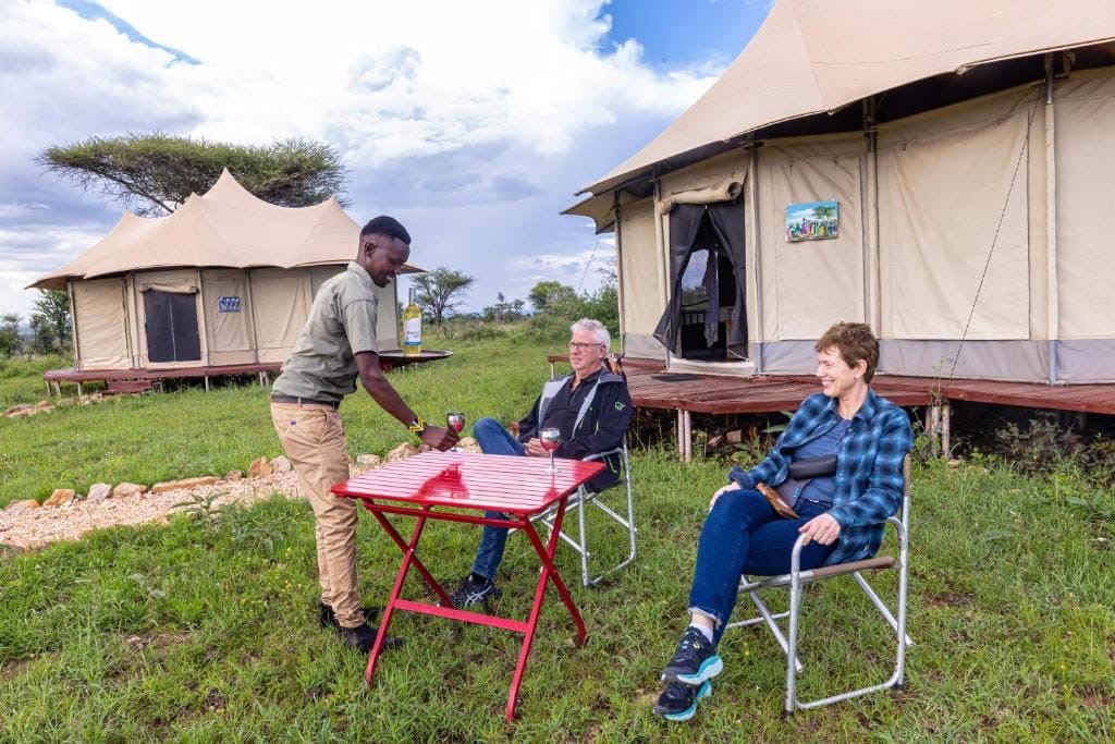 Guests being served refreshments outside their tents at a bush camp