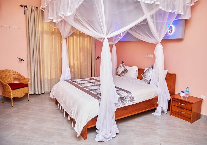 A lodge bedroom with a draped mosquito net and bedside lamps